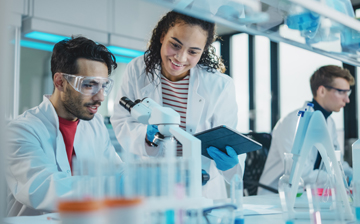 Three students working at a lab bench with a microscope