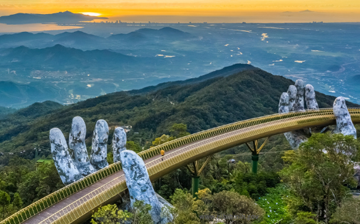 A mountain landscape with giant stone hands holding a bridge across a valley between two peaks.